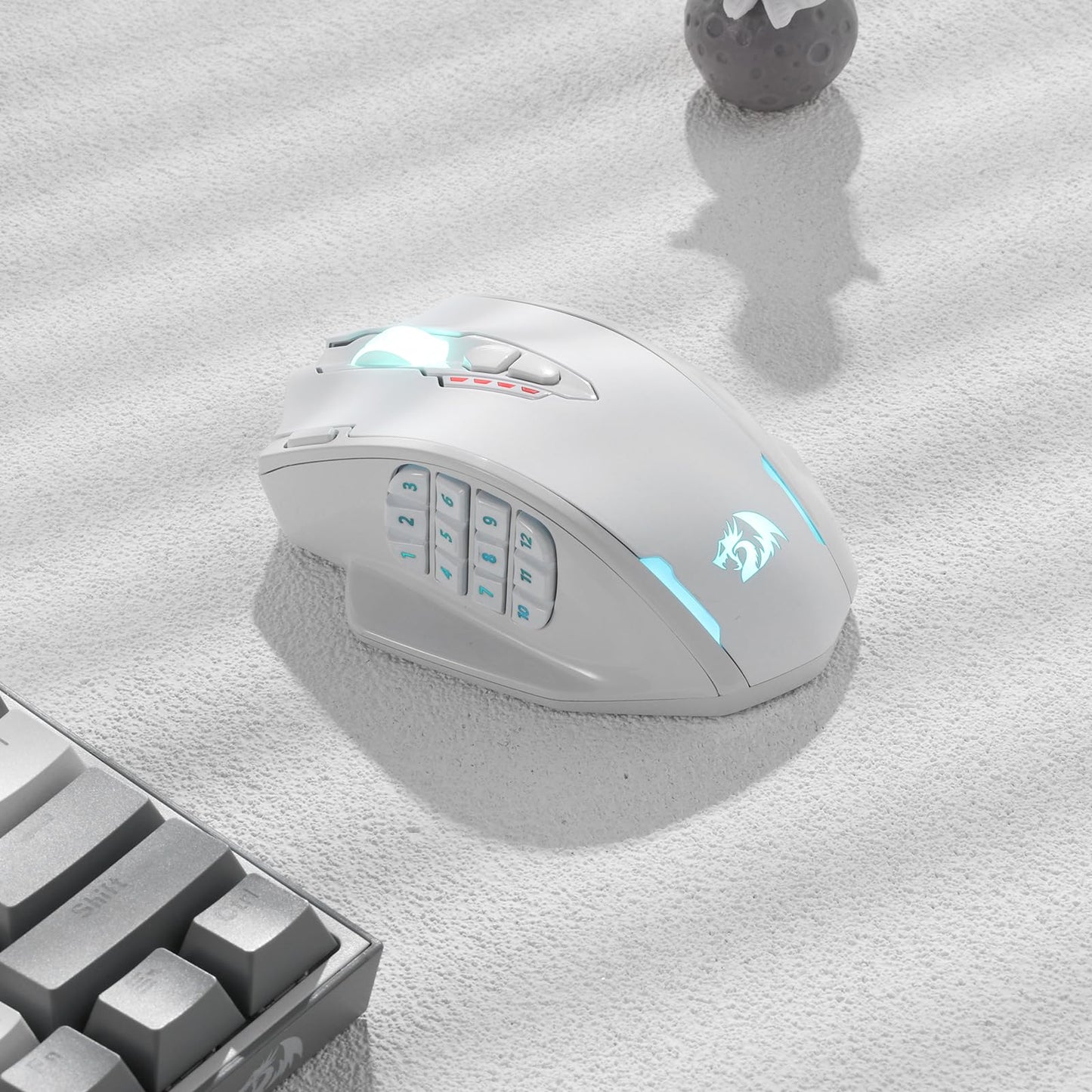 Redragon EU, A white gaming mouse with RGB lighting on a light grey surface next to a keyboard.