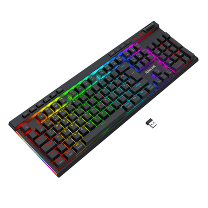 Eine mechanische Gaming-Tastatur in Standardgröße mit schwarzen Tastenkappen und lebhafter RGB-Regenbogen-Hintergrundbeleuchtung, abgebildet vor einem einfarbigen schwarzen Hintergrund. Im Bereich der Leertaste ist der Markenname „TUXEMOTION“ zu sehen.