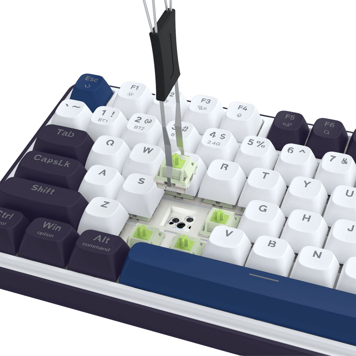 This image shows a keyboard (with white and dark purple keycaps) mid-customization: a tool is removing a green switch from the PCB, highlighting the hot-swap socket design that allows easy switch replacement.
