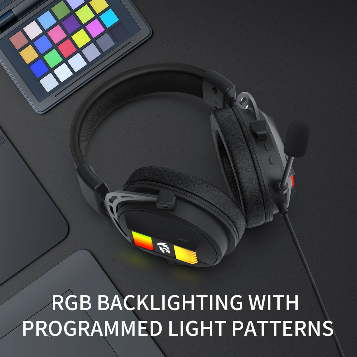 Redragon EU Black gaming headset with RGB backlighting on a dark surface next to a laptop.