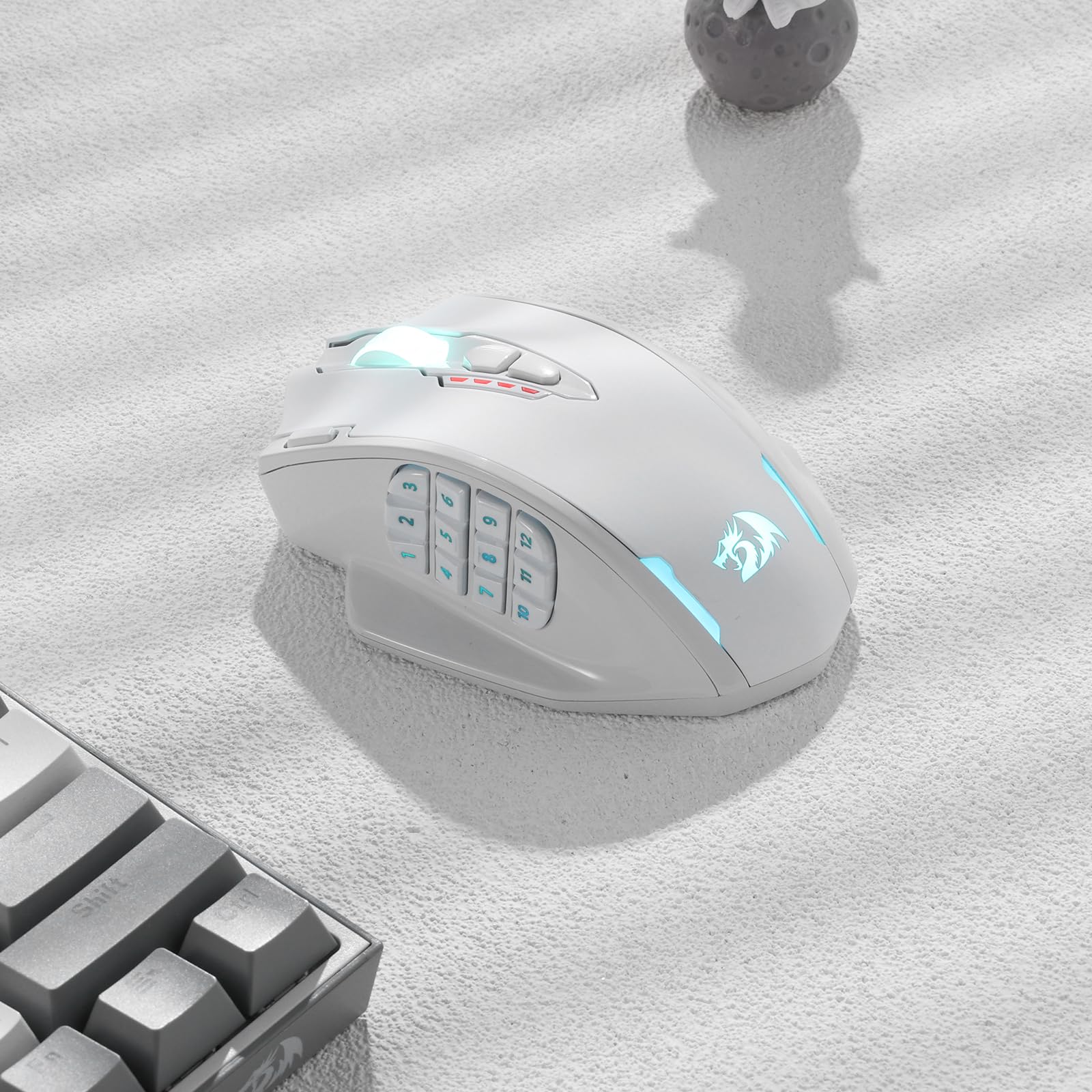 Redragon EU, A white gaming mouse with RGB lighting on a light grey surface next to a keyboard.