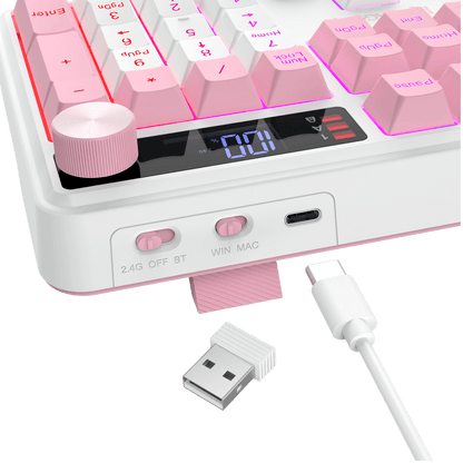 White and pink mechanical keyboard with pink backlighting, a pink rotary knob, a digital display, and a pink USB-C charging port. A pink USB cable and a small USB receiver are shown in front on a black background.
